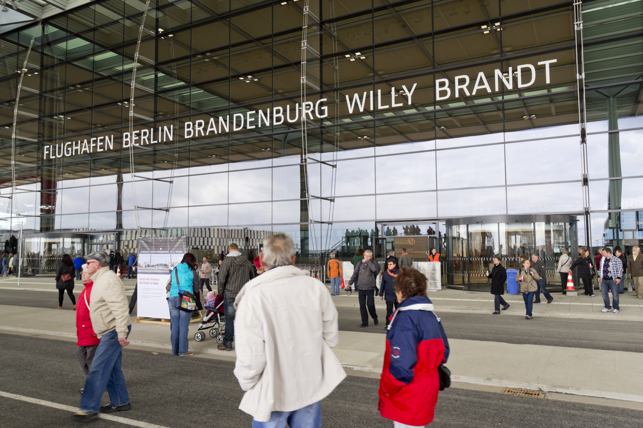 Hovedindgangen til Berlin Brandenburg Willy Brandt Lufthavn med mange mennesker i forgrunden.