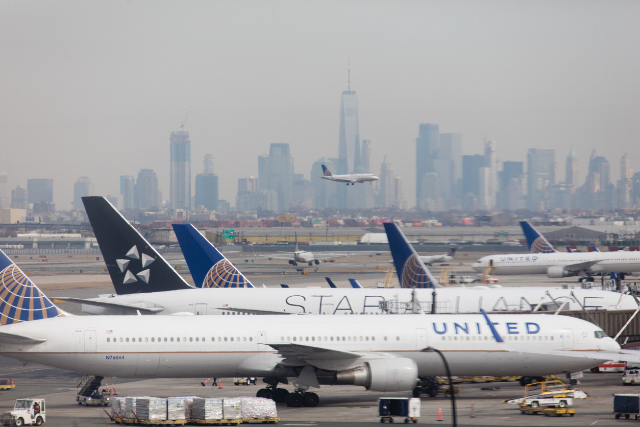 En asfaltbane med et fly, der lander, og Manhattans skyline i baggrunden.