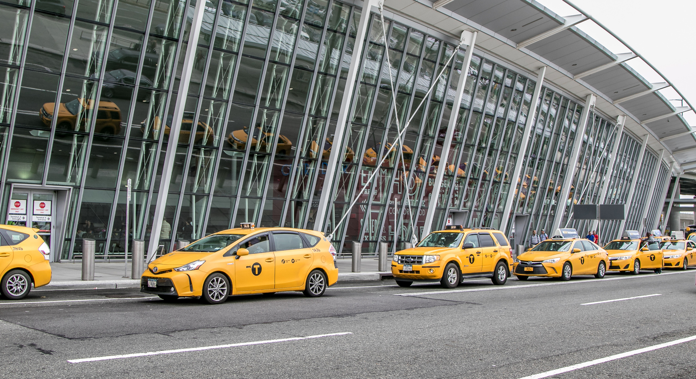 Flere parkerede Yellow Cabs på række uden for en lufthavn i New York.