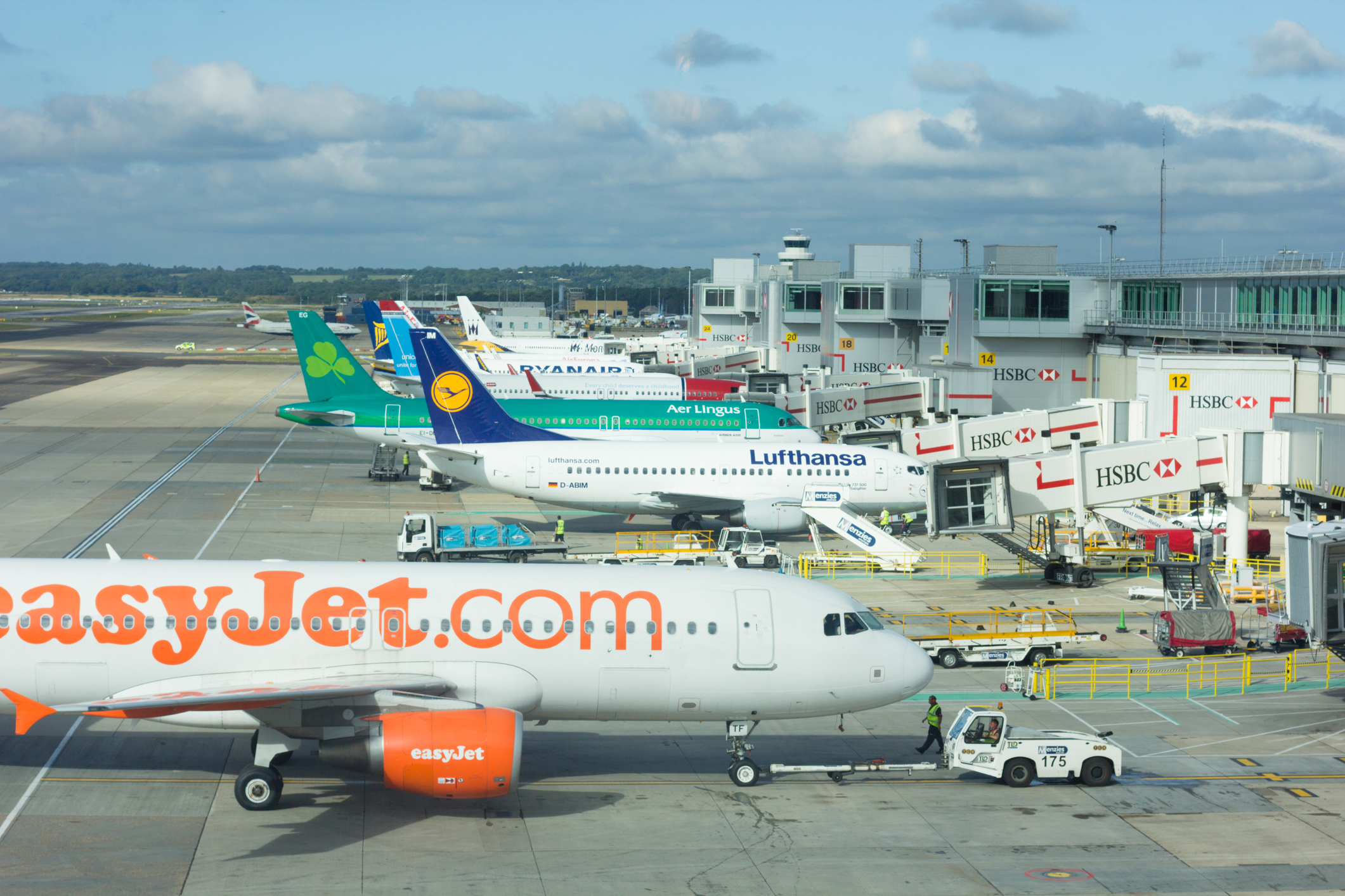 Flere fly fra forskellige flyselskaber står i kø bag hinanden ved deres respektive gates.