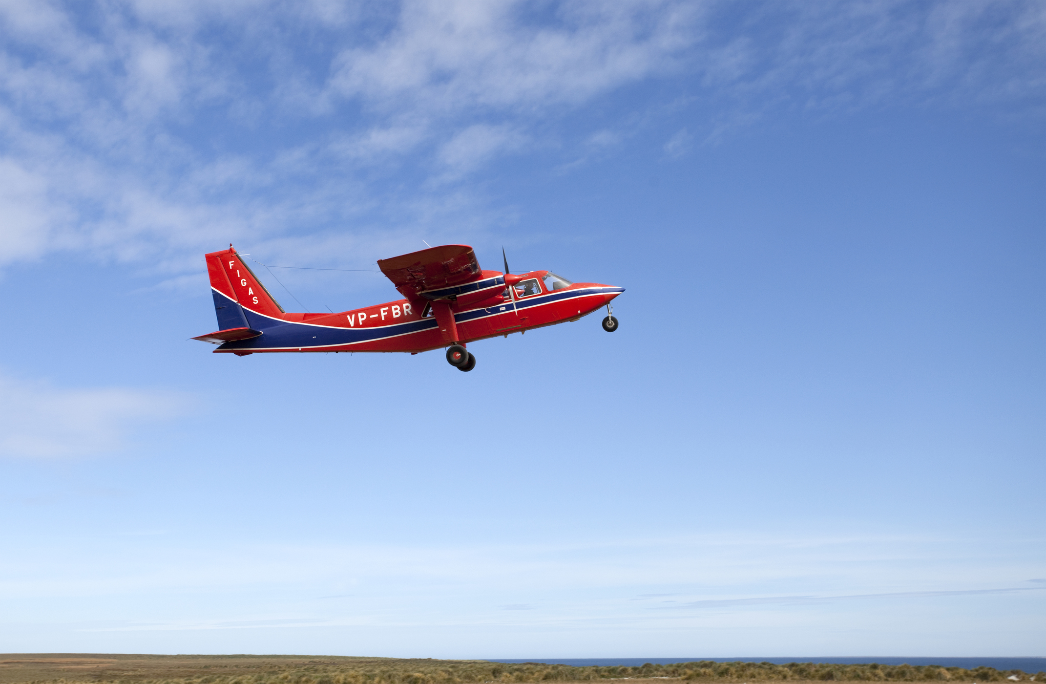 Et rødt og blåt propelfly letter i godt vejr.