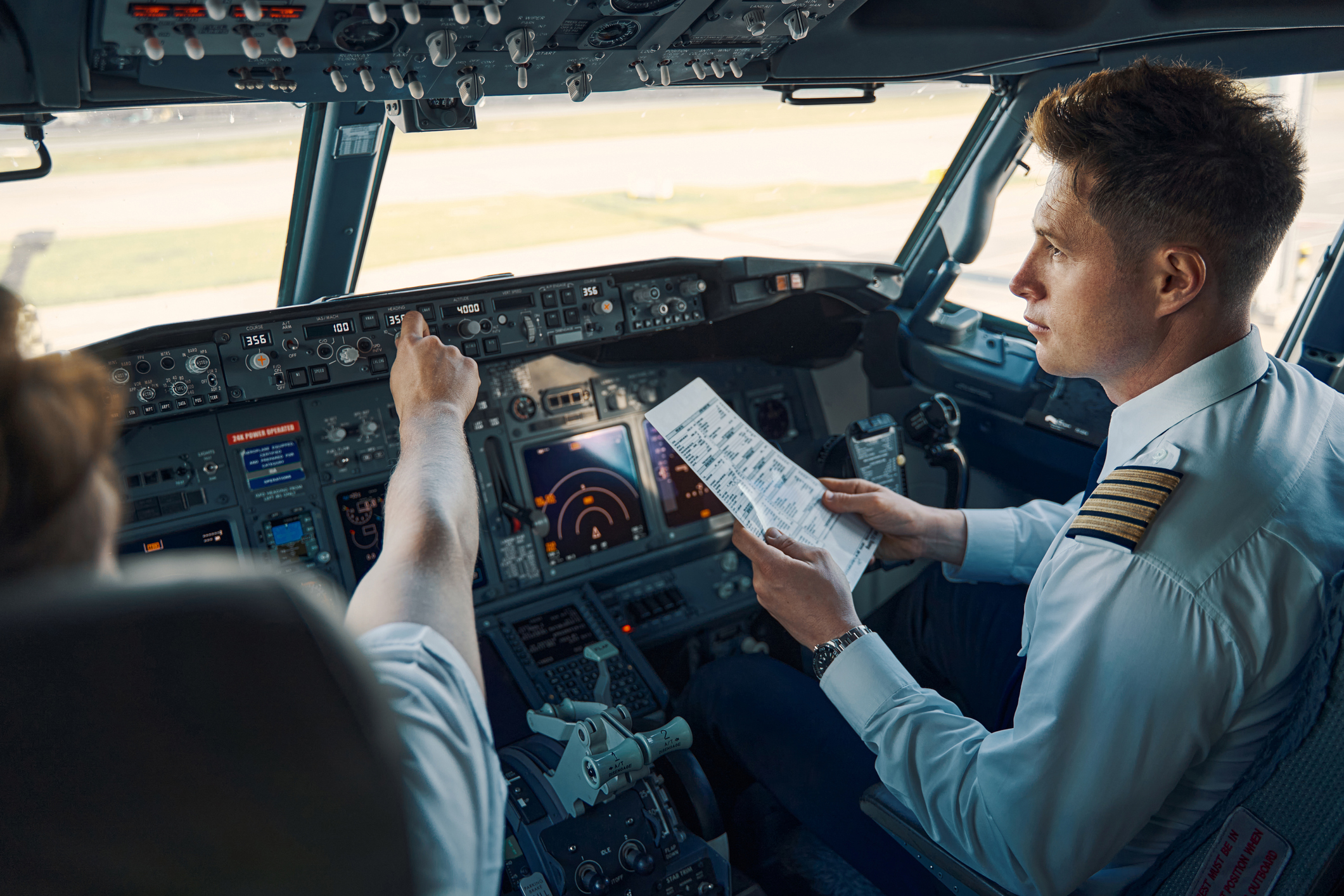 Co-pilot med en tjekliste for flyvningen, siddende ved siden af chefpiloten i cockpittet