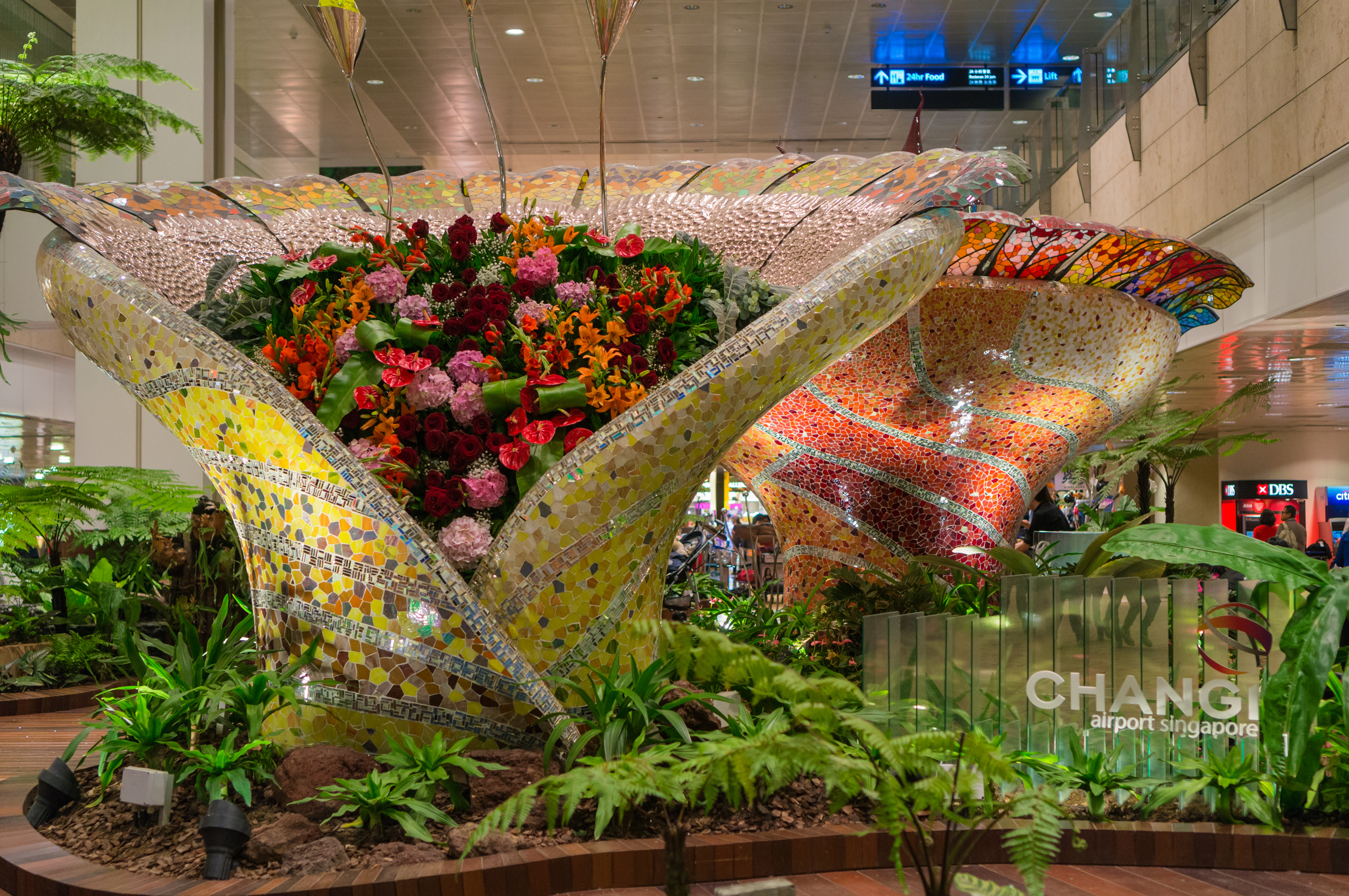 To meget store blomsterkasser dekoreret med udsmykkede mosaikker i Changi Lufthavn.