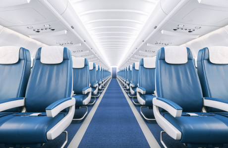 Tom gang i et helt tomt fly med blåt gulvtæppe, hvidt loft og blå og hvide lædersæder