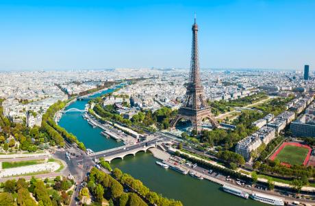 Et luftfoto af Paris, i forgrunden kan man se Eiffeltårnet og Seinen, i baggrunden strækker byen sig.