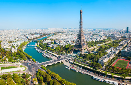 Et luftfoto af Paris, i forgrunden kan man se Eiffeltårnet og Seinen, i baggrunden strækker byen sig.