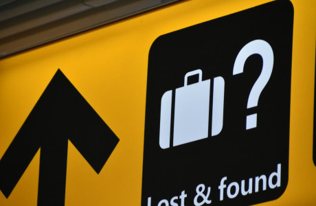 Gult vejviserskilt i en lufthavn med hvid skrift "Lost & Found" og en kuffert afbildet i hvidt på en sort baggrund