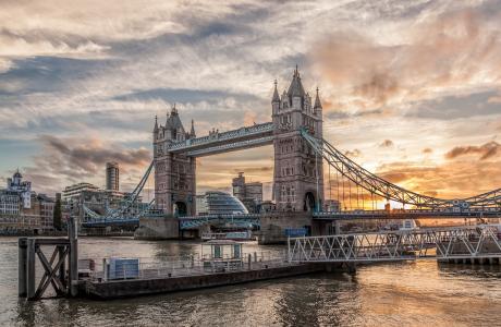 Tower Bridge i London i en dramatisk solopgang, med en gangbro i forgrunden.