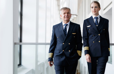 En stewardesse og en ung stewardesse i blå uniform går side om side fra terminalen til flyet for at gøre alt klar til afgang.