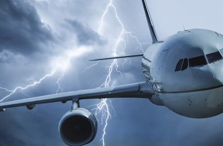 Et fly fly flyver gennem en tordensky, lynene blinker i baggrunden.